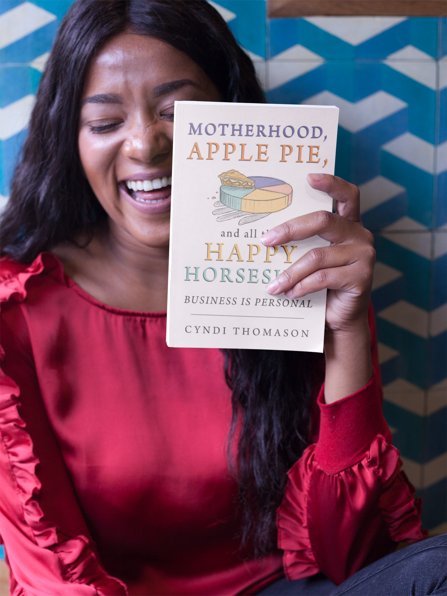 Image of woman excited to be holding the book motherhood, Apple Pie and All That Happy Horseshit.
